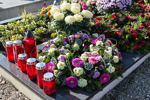 Frisches Grab mit Kerzen und Blumenschmuck